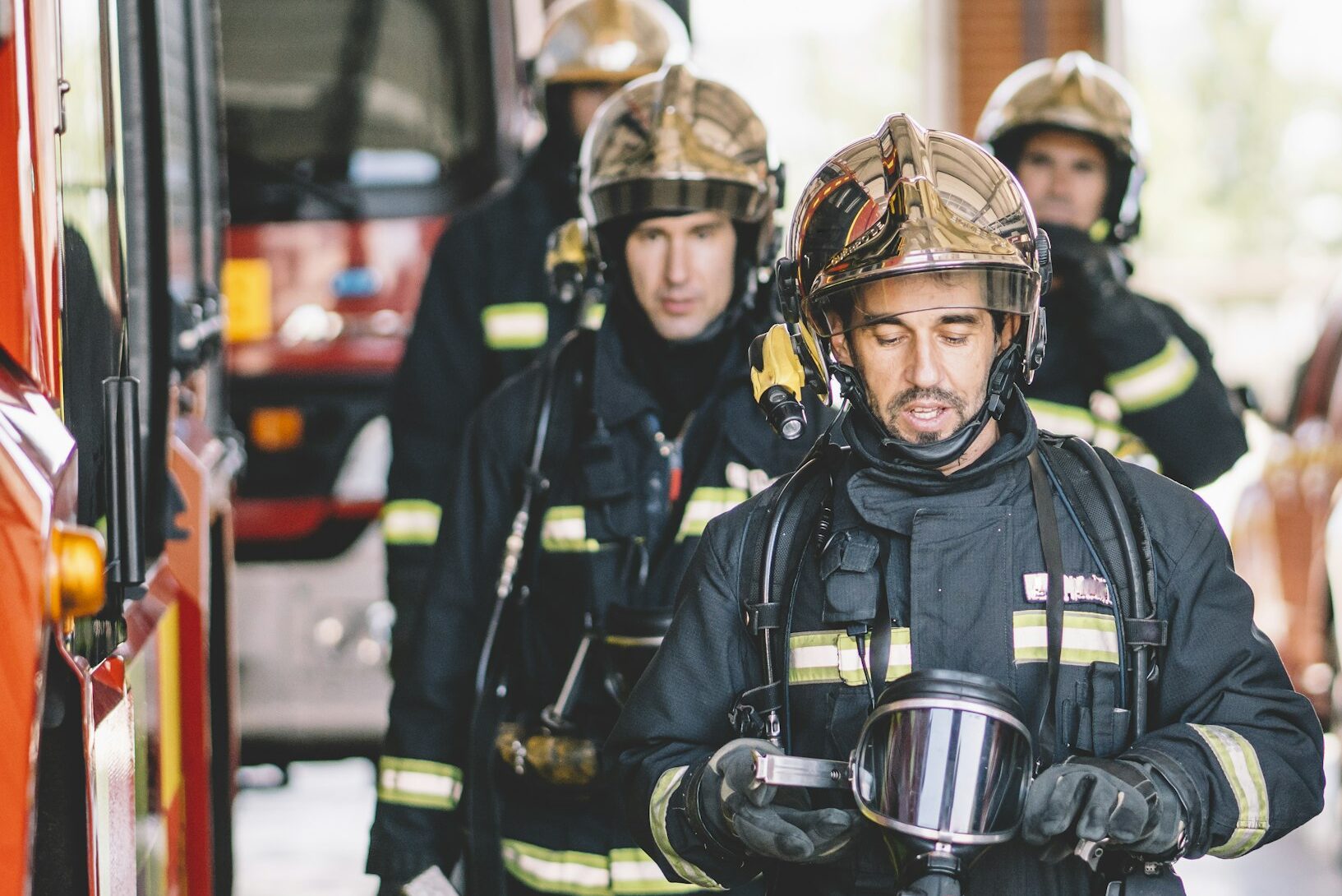 Firefighters in helmets and uniforms preparing for action inside a fire station, emphasizing emergency response and teamwork.